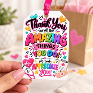 May include: A white rectangular gift tag with a pink ribbon, featuring colorful text that reads Thank You for all the AMAZING THINGS YOU DO! We Truly APPRECIATE YOU! Decorated with illustrations of a pink heart stethoscope, a clipboard, and stars.