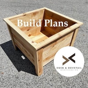 May include: A wooden planter box with the text "Build Plans" in white. The box is made of light-colored wood and has a square shape. The logo for Duck & Dovetail Woodworking is in the bottom right corner.