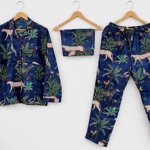 Puede incluir: Conjunto de pijama de tres piezas en tejido azul oscuro, con estampado de tem&aacute;tica selv&aacute;tica con leopardos, cebras, p&aacute;jaros y plantas tropicales. El conjunto incluye una camisa abotonada, un pantal&oacute;n corto y un pantal&oacute;n.