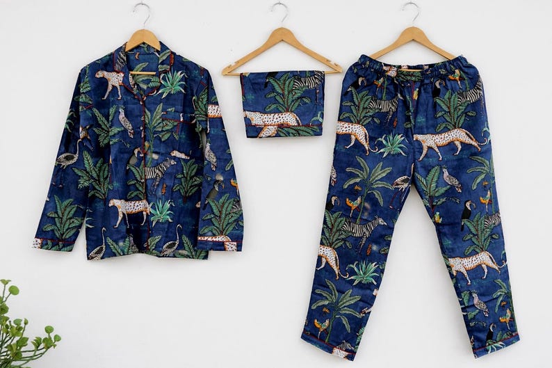 Puede incluir: Conjunto de pijama de tres piezas en tejido azul oscuro, con estampado de tem&aacute;tica selv&aacute;tica con leopardos, cebras, p&aacute;jaros y plantas tropicales. El conjunto incluye una camisa abotonada, un pantal&oacute;n corto y un pantal&oacute;n.