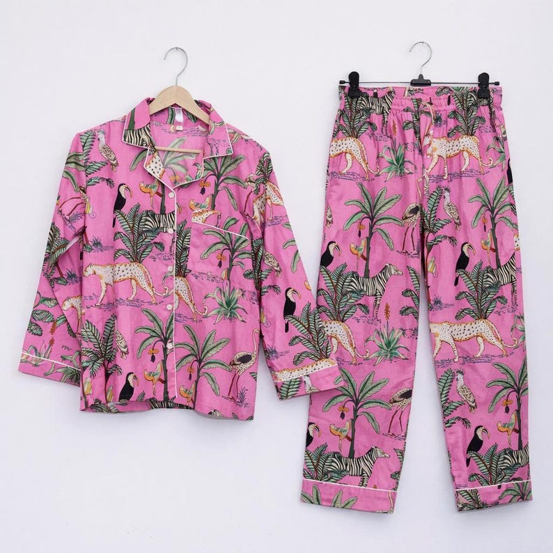 Puede incluir: Conjunto de pijama rosa con estampado de jungla con tucanes, cebras, leopardos y palmeras. La camisa de manga larga y el pantal&oacute;n tienen ribetes blancos. El conjunto est&aacute; hecho de una tela suave y ligera.