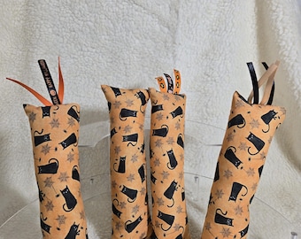 May include: Four orange cat toys with black cat and spiderweb patterns. Each toy has a ribbon with the text "HAPPY HALLOWEEN". The toys are rectangular and filled with stuffing, perfect for Halloween.