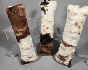 May include: Three faux fur Christmas stockings in shades of brown and white. The stockings have a soft, textured appearance, with a mix of solid and patterned sections. Each stocking has a different pattern and colour combination, creating a rustic, cosy feel.