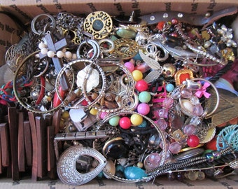 May include: A box filled with a variety of colorful jewelry, including earrings, necklaces, bracelets, and rings. The jewelry is made of different materials, such as metal, glass, and plastic.