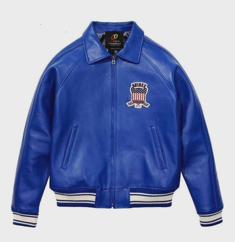 May include: A vibrant blue leather jacket with a classic collar and a zip-up front. The jacket features a patch on the chest with a patriotic design and the word "AVIREX". The cuffs and hem have white and navy stripes.