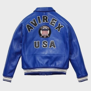 May include: A vibrant blue leather jacket with the word "AVIREX" arched across the shoulders. Below the logo is a patch with the words "ALL AMERICANS" and "USA" in white lettering. The jacket has white and blue striped cuffs.