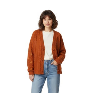 Könnte beinhalten: Ein rostfarbener Zopfstrick-Cardigan mit Sternakzenten am linken Ärmel. Der Pullover hat eine Knopfleiste vorne und wird über einem weißen T-Shirt und einer blauen Jeans getragen. Der Cardigan ist ein warmer, gemütlicher Stil.