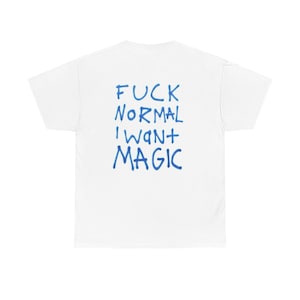 Puede incluir: Camiseta blanca con el texto azul "FUCK NORMAL I WANT MAGIC" en un estilo manuscrito. La camiseta está hecha de un material suave y tiene mangas cortas y cuello redondo.