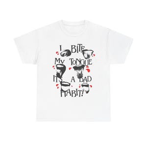 Pode incluir: Camiseta branca com um design gráfico. O design inclui ilustrações pretas de bocas e o texto "I BITE MY TONGUE IT'S A BAD HABIT!" em preto, com detalhes em vermelho. Uma peça de roupa casual.