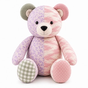 May include: A plush teddy bear featuring a split-design body with one side in a light purple floral print and the other in a pink abstract pattern. It has a sage green gingham foot, a pink polka dot foot, black eyes, and a black stitched nose.