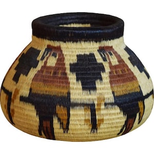 May include: Handwoven basket with a wide base and a narrow, dark rim. The basket features a repeating pattern of stylized figures in shades of brown, black, and tan. The basket is made of natural fibers.