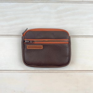 Cartera de hombre de piel marrón con cremallera y tres bolsillos.