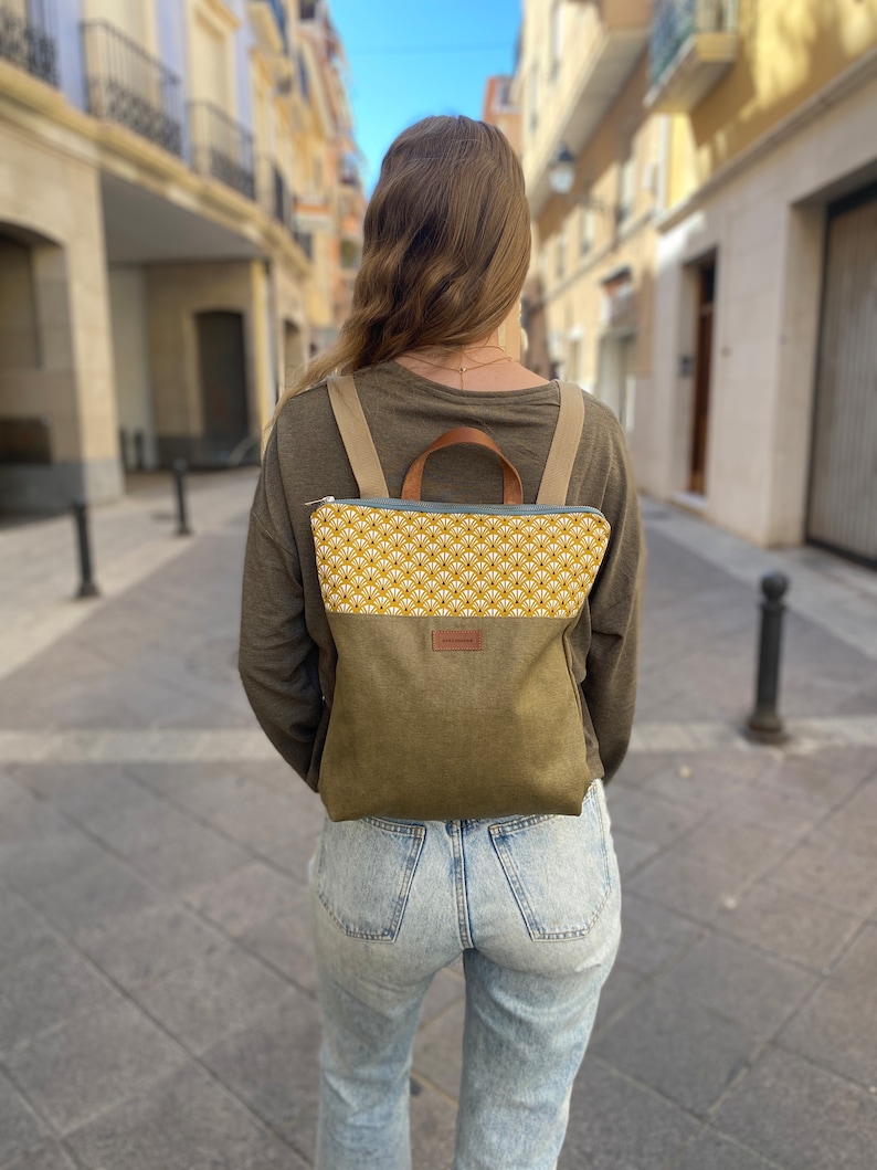 young girl with a mustard and green backpack walking down a European street
