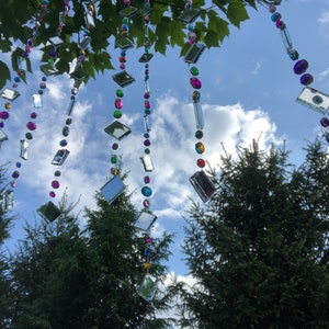 Beautiful hanging strings adorned with mirrors and colorful rhinestones that will hang from low tree branches.  They dangle freely and will move with the breeze, casting whimsical reflections throughout your outdoor space.  Whimsical colorful art