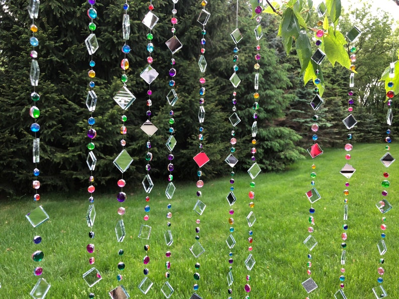 Beautiful hanging strings adorned with mirrors and colorful rhinestones that will hang from low tree branches.  They dangle freely and will move with the breeze, casting whimsical reflections throughout your outdoor space.  Whimsical colorful art