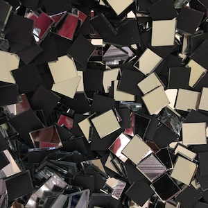 May include: A pile of small, square mirror tiles, some with a silver reflective surface and some with a black backing.