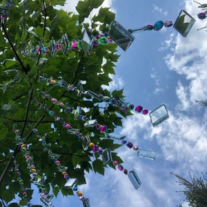 Beautiful hanging strings adorned with mirrors and colorful rhinestones that will hang from low tree branches.  They dangle freely and will move with the breeze, casting whimsical reflections throughout your outdoor space.  Whimsical colorful art