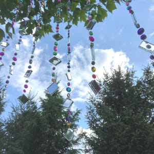 Beautiful hanging strings adorned with mirrors and colorful rhinestones that will hang from low tree branches.  They dangle freely and will move with the breeze, casting whimsical reflections throughout your outdoor space.  Whimsical colorful art