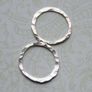 May include: Two silver rings with a hammered texture. The rings are simple and minimalist.
