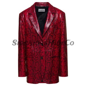 Pode incluir: Um blazer vermelho com padrão de pele de cobra e fecho de dois botões. O casaco tem lapelas entalhadas, dois bolsos frontais e mangas compridas. O forro interior é preto. A marca "ScansionMeCo" é visível.