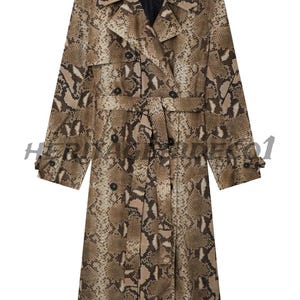 Puede incluir: Un abrigo largo tipo trench de doble botonadura con estampado de piel de serpiente en tonos marrón y beige. El abrigo tiene cinturón, solapas con muescas y puños abotonados. Es una prenda de vestir exterior elegante.