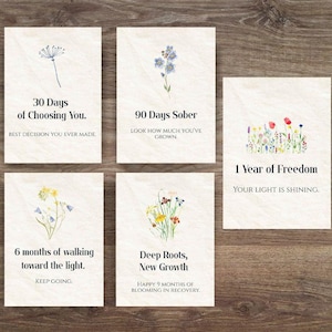 Puede incluir: Cinco tarjetas rectangulares con ilustraciones florales en acuarela y texto. Las tarjetas dicen: "30 días de elegirte", "90 días sobrio", "1 año de libertad", "6 meses caminando hacia la luz" y "Raíces profundas, nuevo crecimiento".