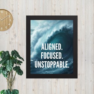 May include: A framed print with a black border features a dynamic image of a large ocean wave in shades of blue and white. The words "ALIGNED. FOCUSED. UNSTOPPABLE." are printed in white, bold font.