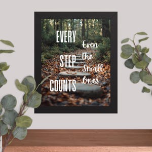 May include: A framed print with the text "EVERY STEP COUNTS" and "Even the Small Ones" in white. The background is a forest path with stone steps and fallen leaves, framed in black.