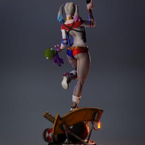 May include: A detailed figurine of a character with a white, red, and blue costume, holding a gun and a plush toy. The figure stands on a base with a mallet, a bomb, and a large yellow blade. The character has blonde pigtails with blue and pink tips.