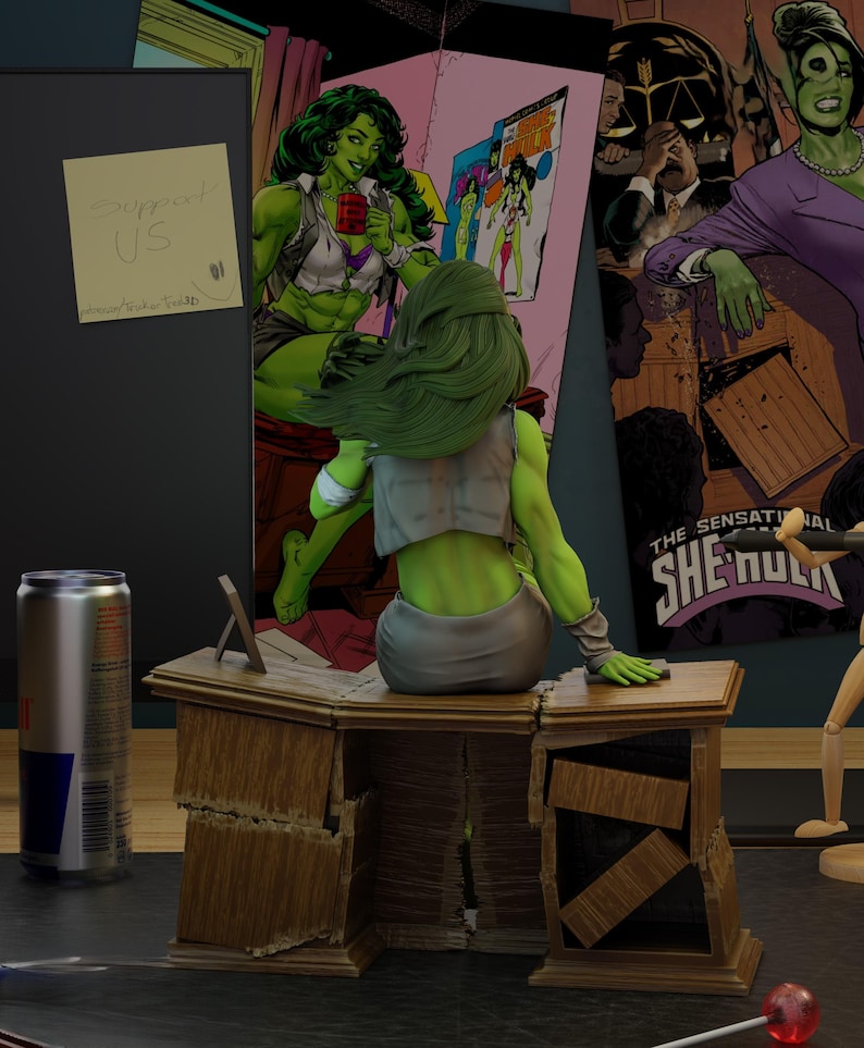 May include: A She-Hulk figurine sits on a wooden desk, with a Red Bull can and comic book art in the background. The desk is distressed, and a sticky note reads "Support US". The scene is a comic book-themed display.