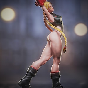May include: A detailed figurine of a female character in a dynamic pose. She wears a black bodysuit, red gloves, and black boots with red trim. Her long blonde hair is styled in braids. The figure is on a dark base.