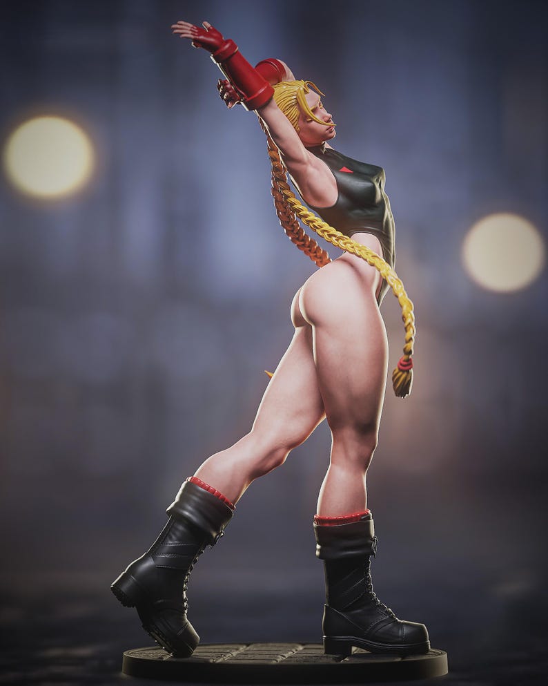 May include: A detailed figurine of a female character in a dynamic pose. She wears a black bodysuit, red gloves, and black boots with red trim. Her long blonde hair is styled in braids. The figure is on a dark base.