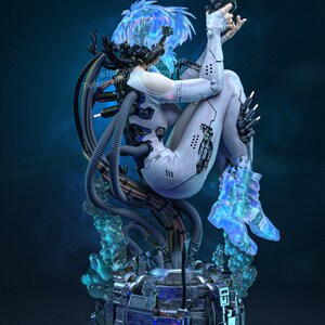 K&ouml;nnte beinhalten: Futuristische Skulptur einer Figur in einem wei&szlig;en Body, die eine Waffe h&auml;lt. Die Figur hat blaue Haare und ist von mechanischen Elementen und leuchtenden blauen Akzenten umgeben. Der Sockel ist eine detaillierte Metallstruktur.