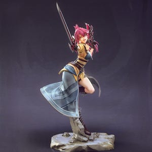 May include: A detailed figurine of a female warrior in a dynamic pose, holding a sword. The figure has pink hair, a yellow and blue outfit, and is standing on a rocky base. The sword is silver with a red accent.