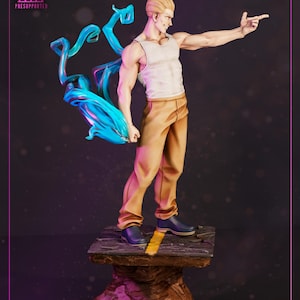 May include: A detailed figurine of a muscular man with blonde hair, wearing a white tank top and tan pants. He is pointing with his right hand, with blue energy effects behind him. The base is a rock-like structure.