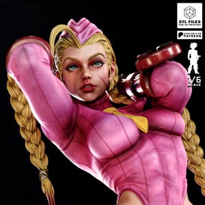 以下が含まれることがあります： ピンク色のボディスーツにブロンドの三つ編みの女性キャラクターの、詳細な1/6スケールフィギュア。フィギュアは決意した表情をしており、赤いオブジェクトを持っています。画像には「STL FILES FOR 3D PRINTING」と「AVAILABLE ON PATREON」というテキストが含まれています。