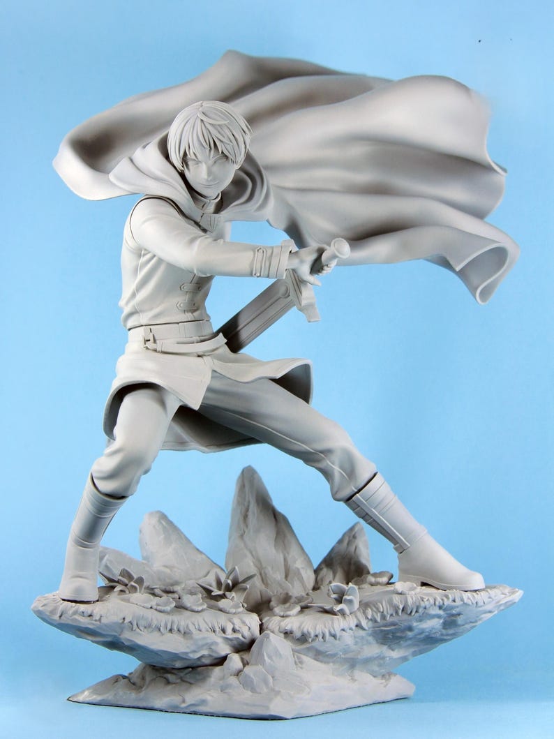 May include: A gray figurine of a person in a dynamic pose, holding a sword. The figure is wearing a long coat with a flowing cape, boots, and pants. The figure is standing on a rocky base with small plants.