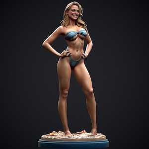 May include: A detailed figurine of a woman in a blue bikini, standing on a sandy base. The figure has long blonde hair and is smiling. The base is a blue oval shape with sand and seashells.