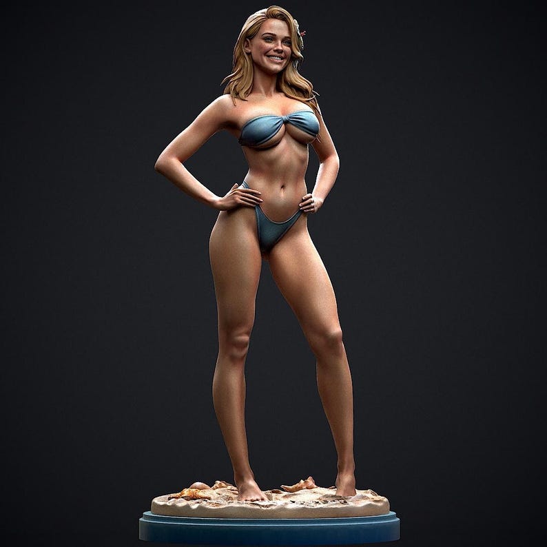 May include: A detailed figurine of a woman in a blue bikini, standing on a sandy base. The figure has long blonde hair and is smiling. The base is a blue oval shape with sand and seashells.