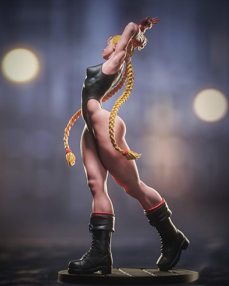 May include: A figurine of a woman in a black bodysuit, black boots, and long blonde braids. The figure is posed with arms raised, showcasing a muscular physique. Red accents are visible on the boots. The background is a blurred gradient of blue and gray with two bright circular lights.