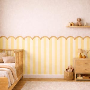 Puede incluir: Una habitación infantil con una cuna de madera, una cómoda y una estantería. La pared presenta rayas verticales amarillas y blancas con un borde de madera festoneado. Un conejito de peluche está sentado en una cesta de mimbre y una lámpara pequeña está en la cómoda.