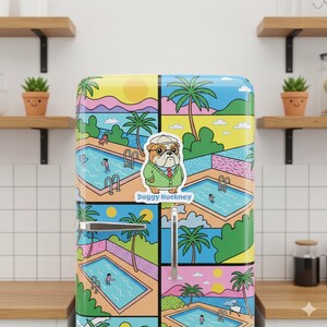 May include: A colorful refrigerator with a vibrant, patterned design featuring swimming pools, palm trees, and a cartoon bulldog sticker that says "Doggy Hockney". The refrigerator has a silver handle and is set against a kitchen backdrop.