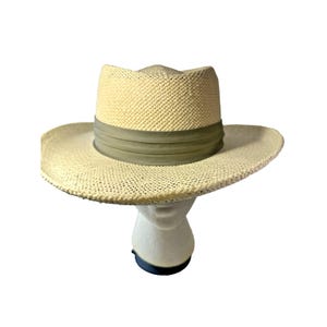May include: A straw fedora hat with a wide brim and a light green band. The hat is displayed on a white mannequin head against a white background. The hat's woven texture is visible.