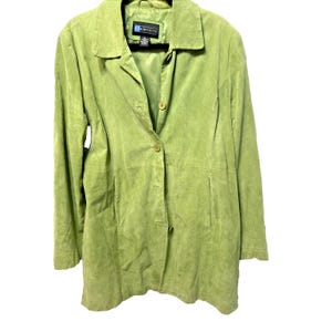 May include: A light green, button-down jacket with a collared neckline. The jacket has long sleeves and a tailored fit. The fabric appears to be a soft suede or corduroy. The jacket has a label that reads "Elegance".