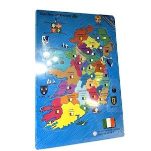 Puede incluir: Un rompecabezas de madera colorido de los condados de Irlanda. El rompecabezas presenta un mapa de Irlanda con cada condado en un color diferente. El texto "Counties of Ireland" está en la parte superior. El rompecabezas está empaquetado en plástico transparente.