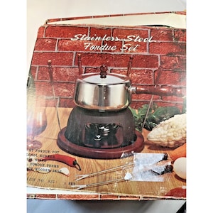 May include: A stainless steel fondue set in its original box. The set includes a pot, burner, stand, and forks. The box has a brick pattern background and the words "Stainless Steel Fondue Set".