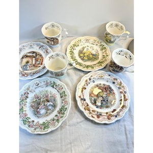 Puede incluir: Un conjunto de tres platos de cerámica y tres tazas a juego con ilustraciones estacionales. Cada pieza muestra escenas detalladas de animales en la naturaleza etiquetadas con las estaciones, con bordes festoneados en cada artículo.