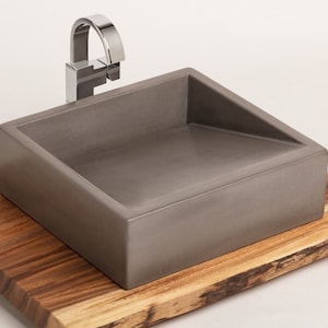 May include: A rectangular concrete sink with a chrome faucet, sitting on a wooden base.