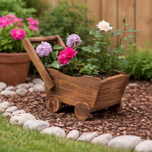 Puede incluir: Un jardinera de madera en forma de vagón, llena de rosas rosas y moradas. La jardinera tiene un asa y dos ruedas de madera. La escena está ambientada al aire libre con una valla de madera y un lecho de mantillo y piedras.