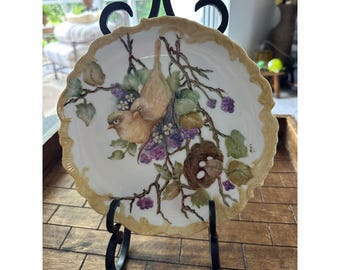 Plato decorativo de porcelana Maris con forma de nido de pájaro pintado a mano, borde festoneado, firmado por Maris, en excelente estado.